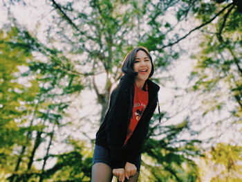 Young woman smiling while standing against trees