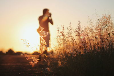 Silhouette man photographing against sky during sunset