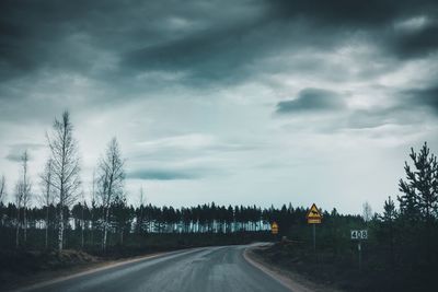 Road by trees against sky