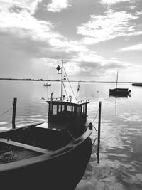 Sailboats moored in sea against sky