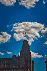 Low angle view of flag and buildings against blue sky