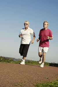 Senior couple jogging together against clear sky