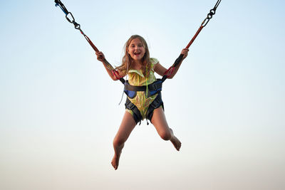 Low angle view of boy swinging against clear sky