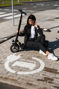 Portrait of woman sitting on footpath