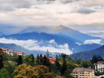 Scenic view of townscape and mountains against sky