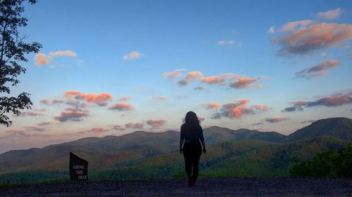 Full length of woman standing on mountain against sky