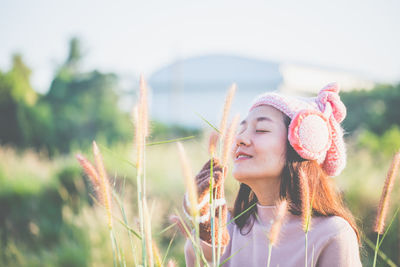 Young woman wearing knit hat holding plant