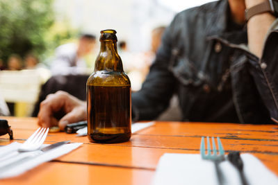 Midsection of man sitting with drink on table