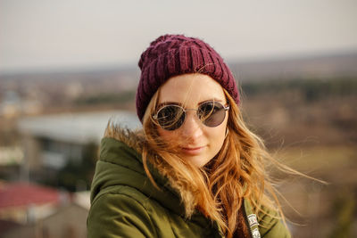 Portrait of young woman in warm clothes wearing sunglasses