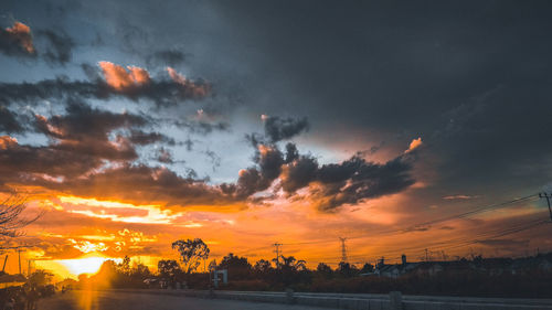 Silhouette trees against dramatic sky during sunset