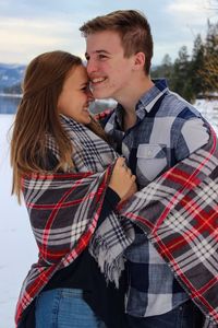 Young couple kissing on snow covered landscape