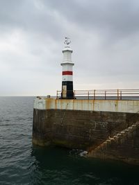 Lighthouse by sea against sky