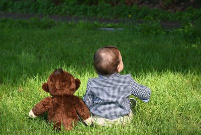 Rear view of girl with teddy bear on field