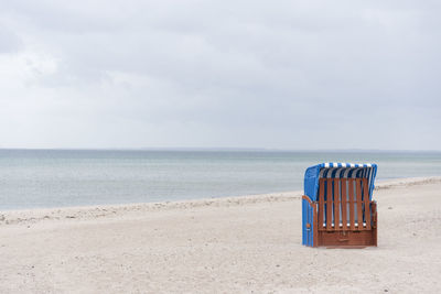 Deck chairs on beach against sky