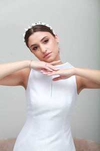 Portrait of young woman standing against white background