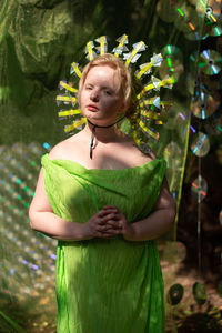 Portrait of young woman standing against plants