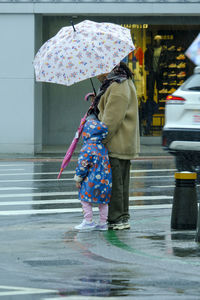 Rear view of woman with umbrella walking on street