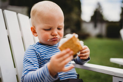 Close up of young boy eating smores with string of melted marshmallows