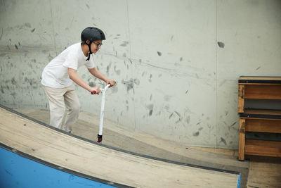 Boy learning how to ride push scooter in indoor skatepark