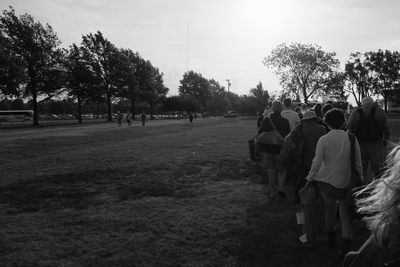 People walking on field against trees in park