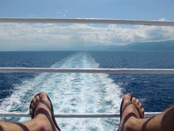 Low section of woman relaxing on sea against sky