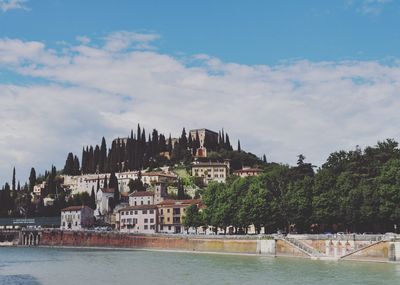 Scenic view of river by buildings in town against sky