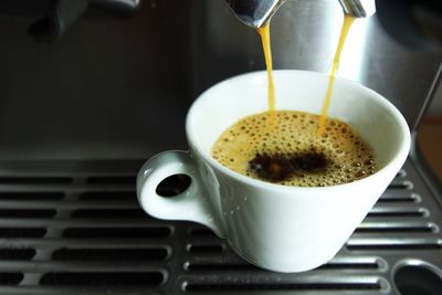 High angle view of coffee falling from espresso maker in cup