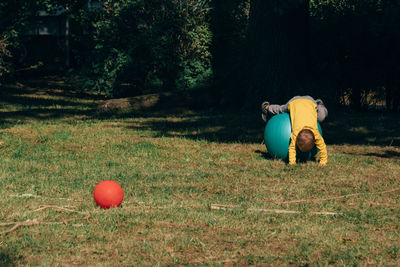 Boy playing with fitness ball on field