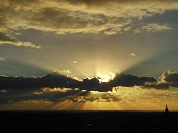 Sun shining through clouds over sea