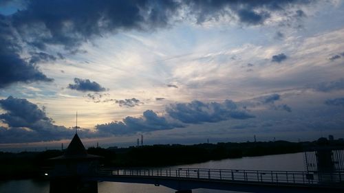Bridge over river against cloudy sky