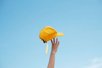 Low angle view of person holding umbrella against blue sky