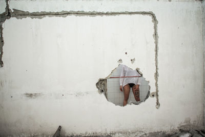 Midsection of woman seen through hole in wall