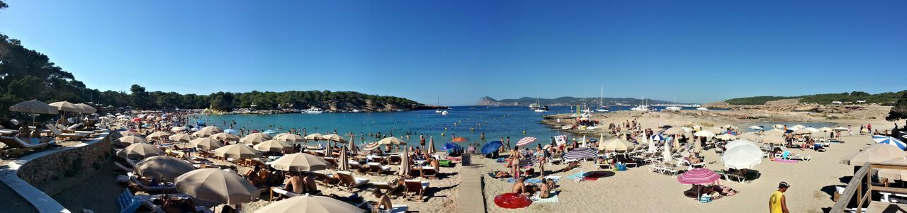 clear sky, copy space, water, large group of people, sea, blue, nautical vessel, transportation, beach, mode of transport, person, boat, men, vacations, moored, leisure activity, high angle view, lifestyles, sunlight