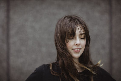 Smiling woman with eyes closed standing outdoors