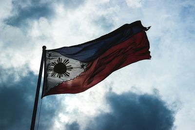 Low angle view of american flag against cloudy sky