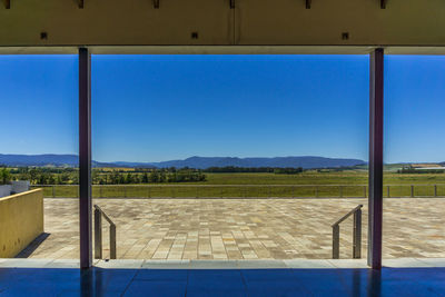 Scenic view of landscape against clear blue sky seen through glass window