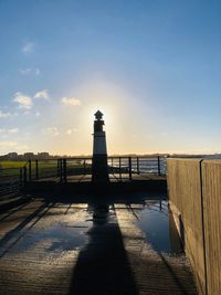 Lighthouse by sea against sky during sunset