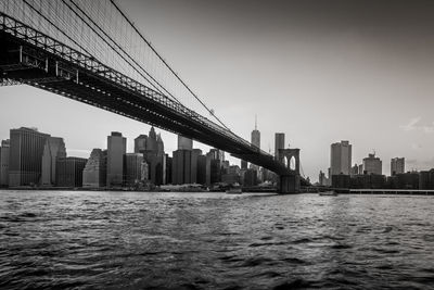 Brooklyn bridge over east river against sky in city