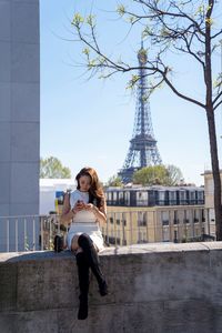 Woman standing by tower in city