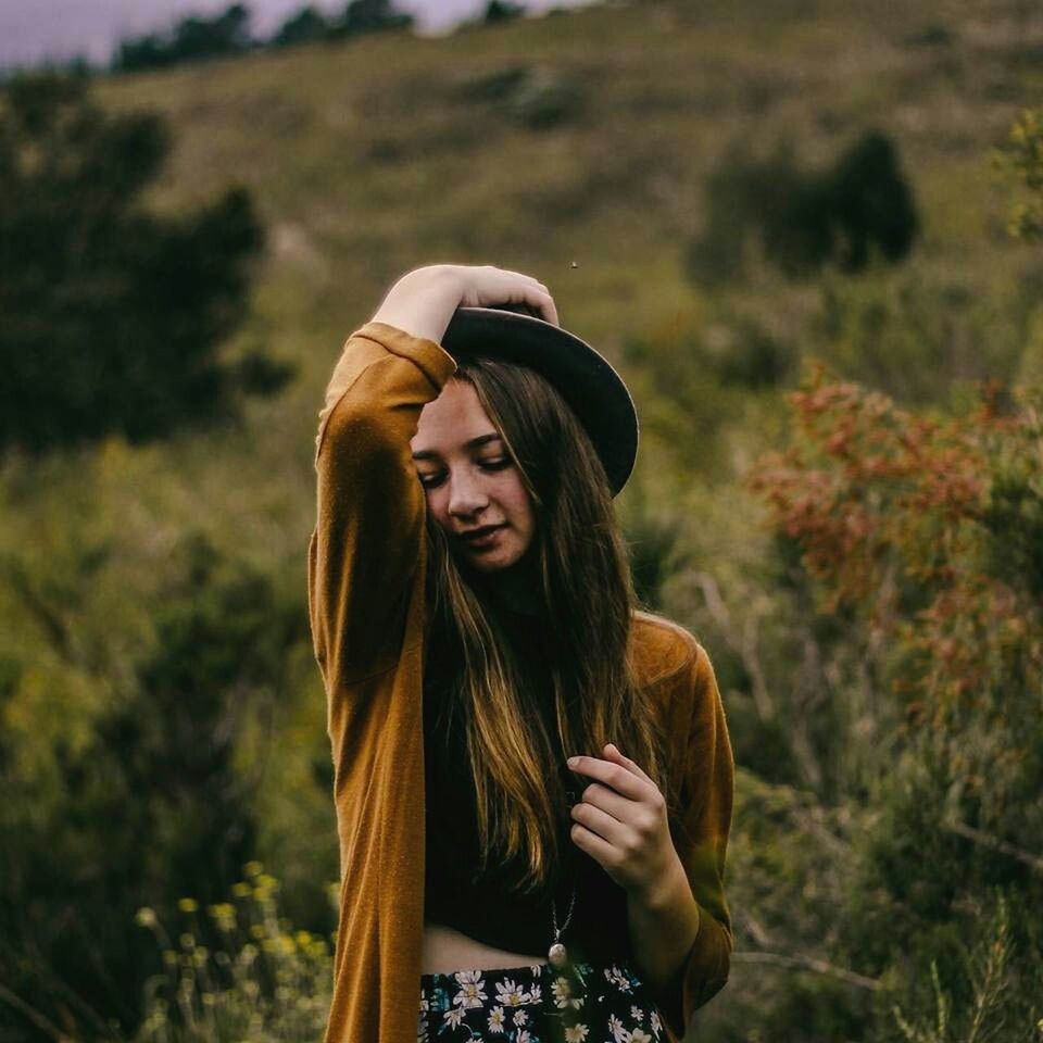 SMILING YOUNG WOMAN STANDING ON GRASS