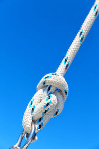 Close-up of rope tied up against blue sky