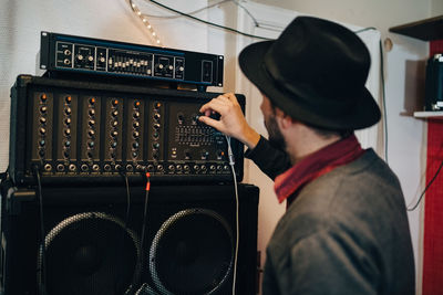 Man adjusting audio equipment while standing at recording studio