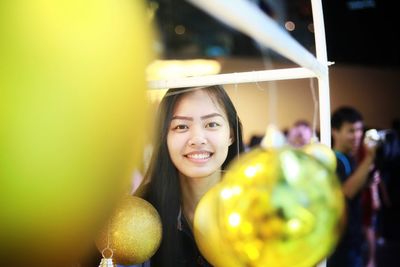 Portrait of smiling young woman with baubles in foreground