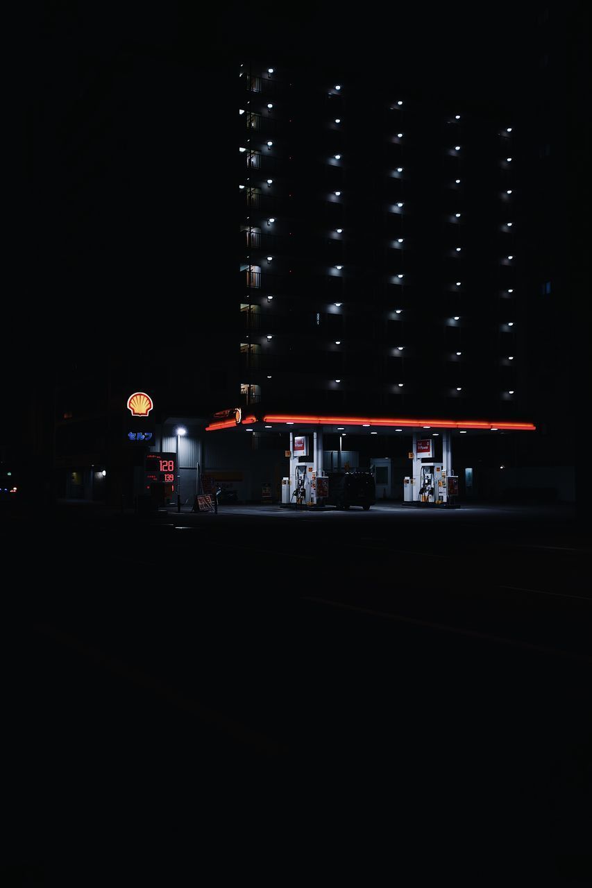 ILLUMINATED ROAD BY BUILDING AT NIGHT