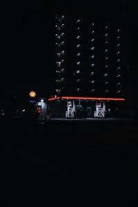 Illuminated road by buildings in city at night