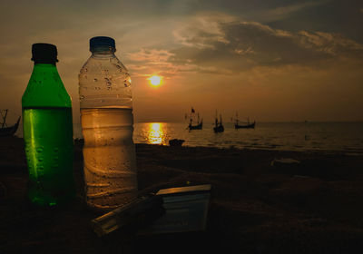 People on table by sea against sky during sunset