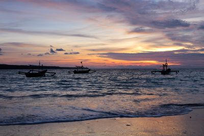 Silhouette boat sailing on sea against sky during sunset