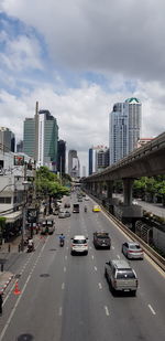 Vehicles on road amidst buildings in city against sky