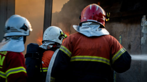 Rear view of firefighters working outdoors