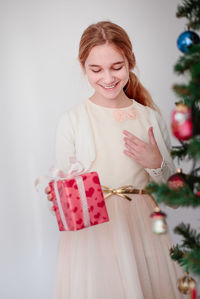 Young woman smiling while standing against white wall